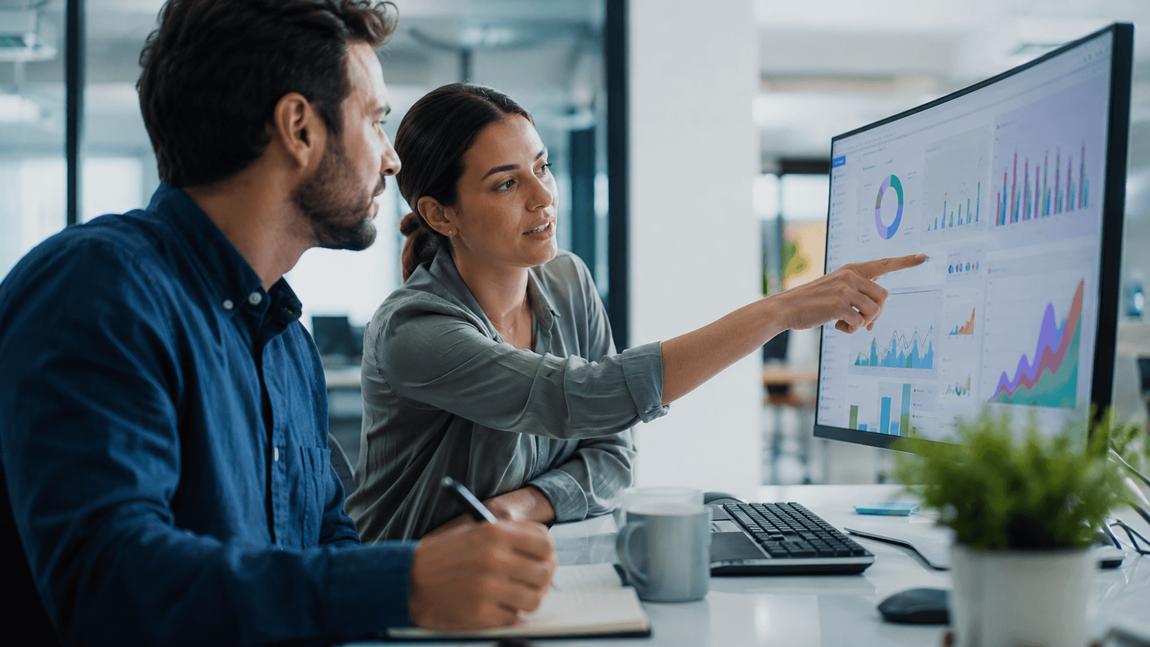Deux collaborateurs consultent des graphiques et indicateurs sur un tableau de bord Power BI pour analyser les données d’entreprise